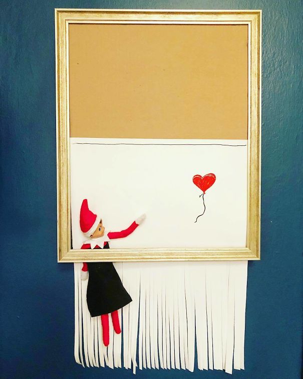 "Elf On The Shelf idea inspired by Banksy's shredded balloon artwork, with the elf in a frame reaching for a red heart balloon as paper shreds below."