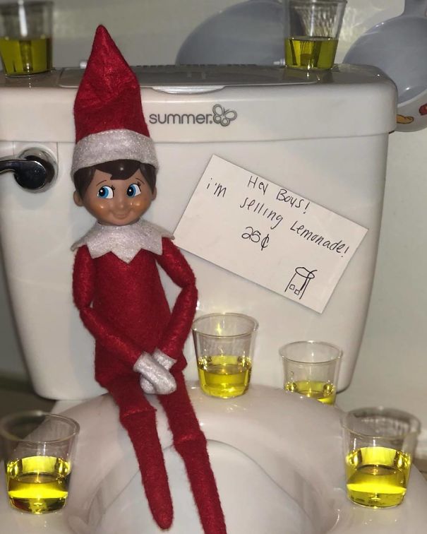 "Elf On The Shelf idea with the elf sitting on a toilet surrounded by cups of yellow 'lemonade,' humorously selling it for 25 cents with a sign."