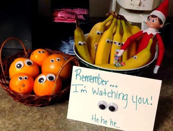 "Elf On The Shelf idea with an elf next to googly-eyed bananas and oranges, holding a sign saying 'Remember... I'm watching you!'"