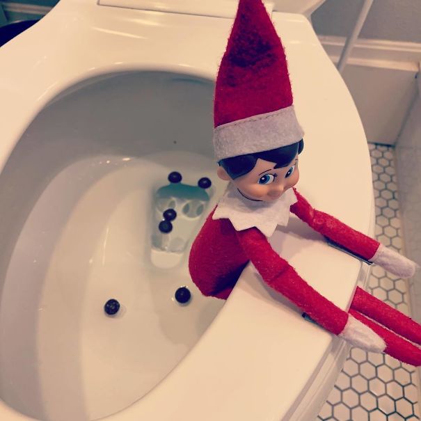 "Elf On The Shelf idea with an elf sitting on the edge of a toilet, surrounded by chocolate candy pieces to mimic a prank in the toilet bowl."