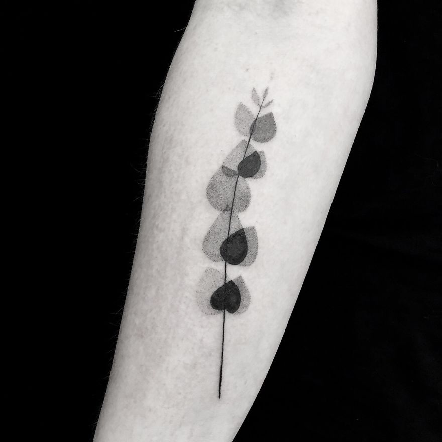 Minimalist botanical tattoo design with simple leaf line art on a forearm.