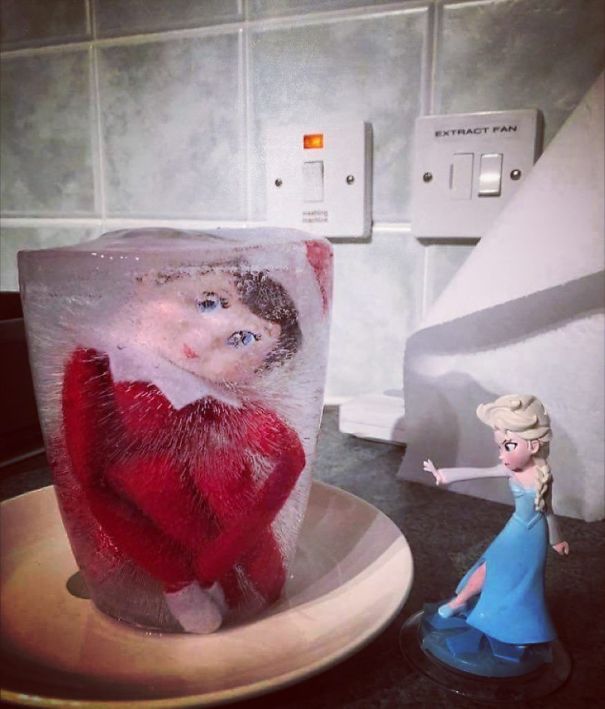 "Elf On The Shelf idea with the elf doll frozen in a block of ice, with an Elsa figurine from Frozen posed as if casting an ice spell nearby."