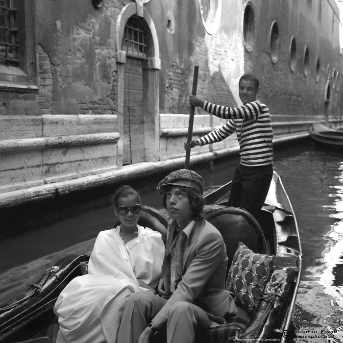 Couple enjoys a gondola ride in Venice canal with gondolier in striped shirt in rare 50s and 60s celebrity photos.