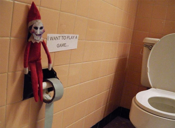 "Elf On The Shelf idea with the elf wearing a creepy mask, next to a toilet paper roll and a sign saying 'I want to play a game...'"