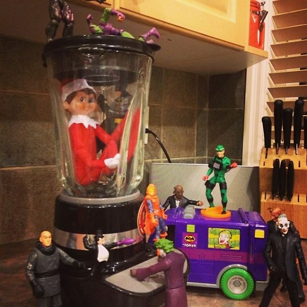 "Elf On The Shelf idea with the elf trapped in a blender surrounded by villain action figures, creating a humorous 'hostage' scene."