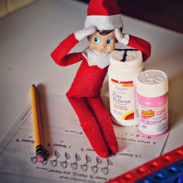 "Elf On The Shelf idea showing an elf holding its head in stress, sitting beside pain reliever and stomach medicine bottles, surrounded by a worksheet and pencil."