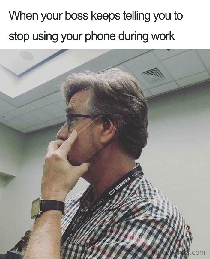 Man with glasses and hearing aid uses his phone in a humorous boss meme.