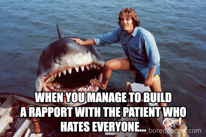Person posing with a large shark mouth prop, humorously depicting a nurse meme about building rapport with patients.
