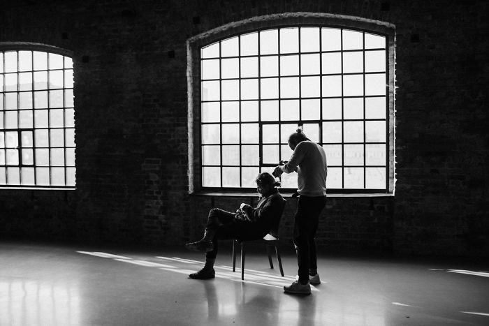 Artist tattoos a seated man in a studio with natural light, part of a motion tattoo project. Artist tattoos a seated man in a studio with natural light, part of a motion tattoo project.