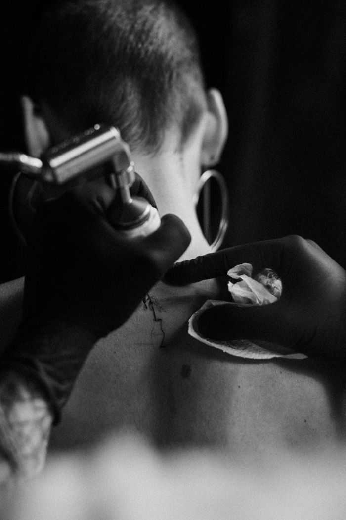 Tattoo artist inks part of a motion tattoo on a person's neck. Tattoo artist inks part of a motion tattoo on a person's neck.