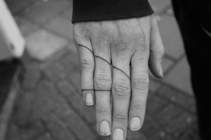 A black line tattoo on fingers, showcasing a trendy design in minimalist style.