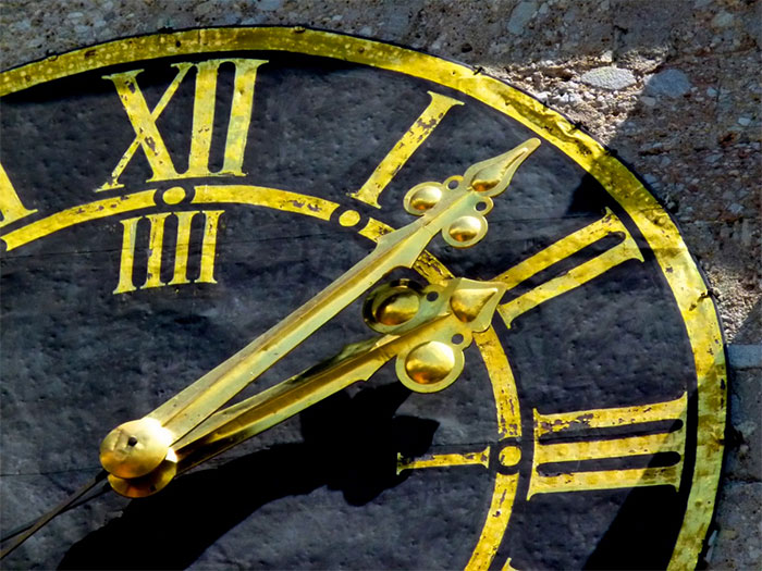 Close-up of an old clock face with gold Roman numerals, illustrating themes of conspiracy theories and hidden time.
