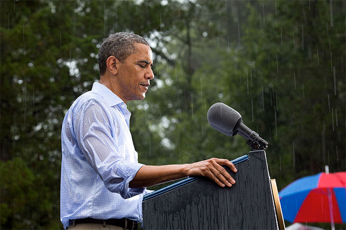 Man speaking at an outdoor podium in the rain, illustrating themes related to crazy conspiracy theories people believe in.