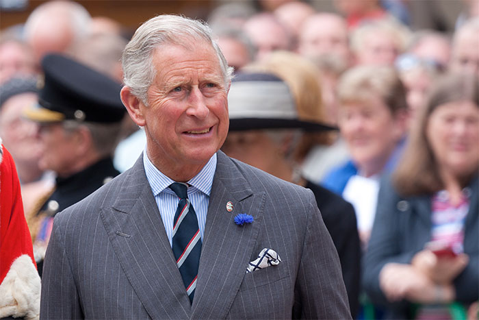 Elderly man in a pinstripe suit and striped tie at a public event with a crowd, related to crazy conspiracy theories.
