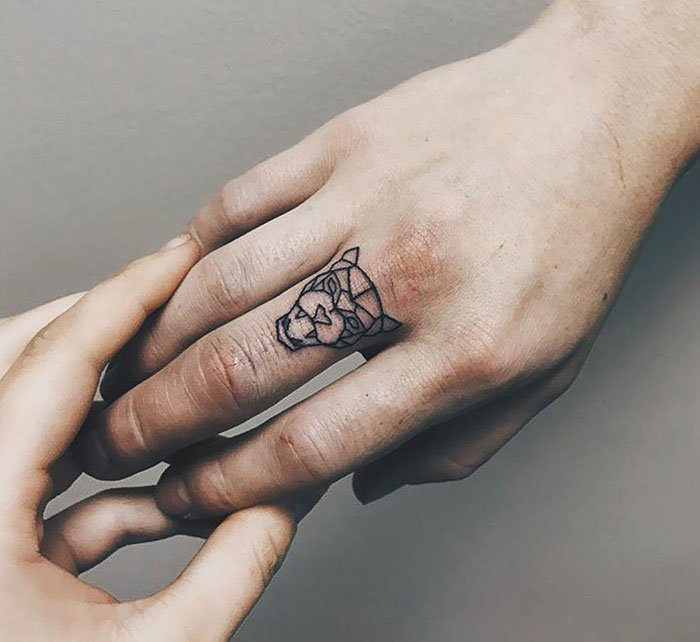 Geometric lion finger tattoo design highlighted as a trendy finger tattoo idea.