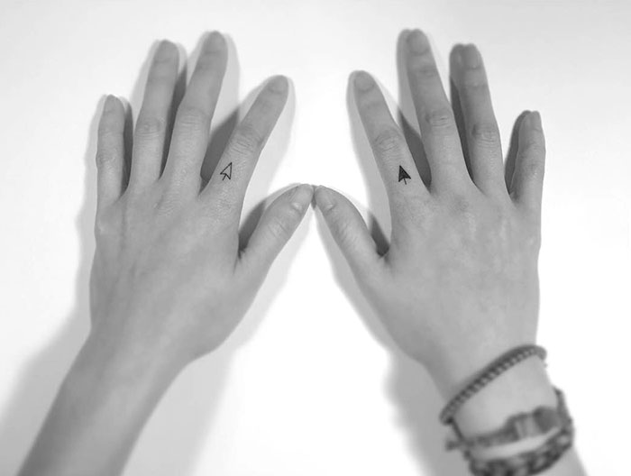 Hands with arrow finger tattoos, showcasing the newest trend in minimalist tattoo ideas.