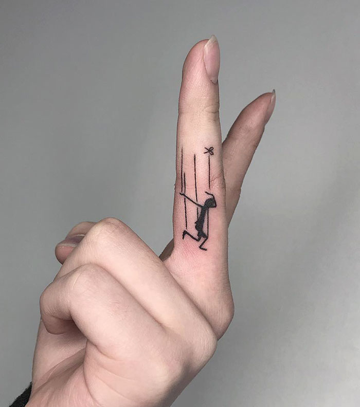 Minimalist finger tattoo of a stick figure on a swing, showcasing trendy finger tattoo design ideas.