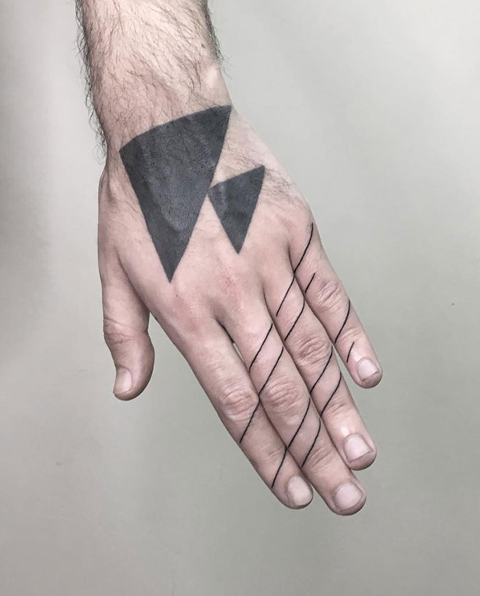 Geometric finger tattoos with black lines and triangles on a hand.