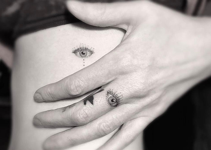 Close-up of hand with finger tattoos, featuring minimalistic eye designs, showcasing the latest tattoo trend.