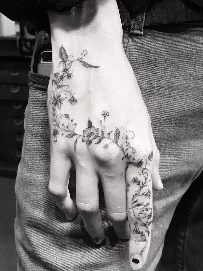 Floral finger tattoos on a person's hand, showcasing intricate designs and trendy patterns.
