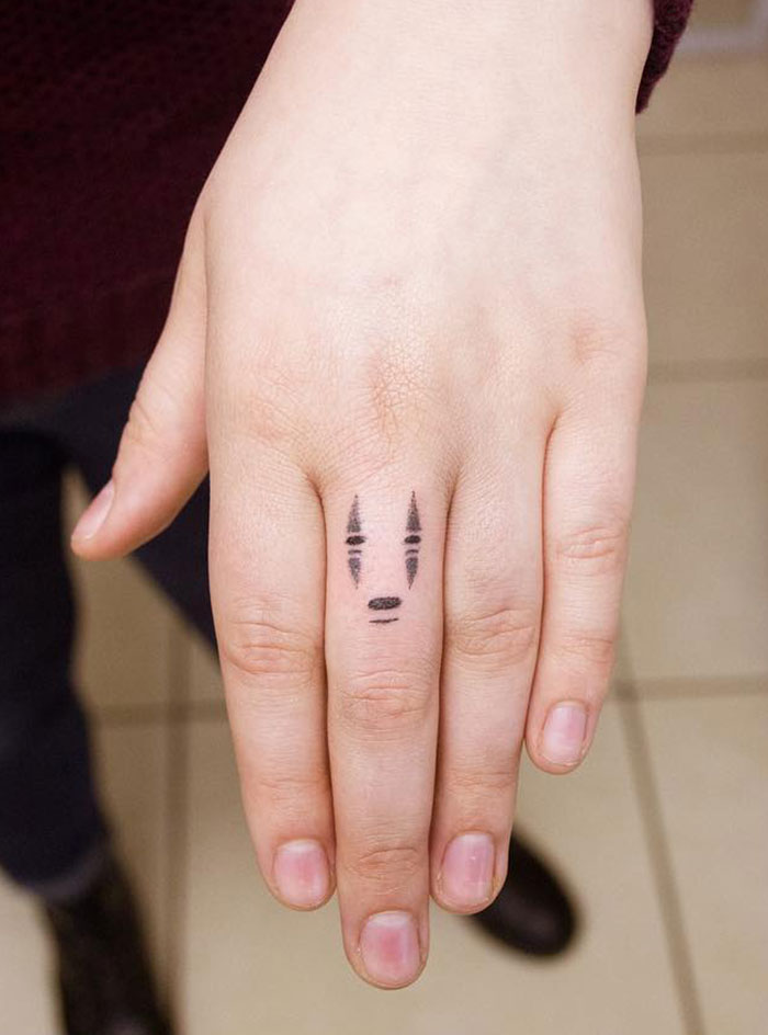 Hand displaying small geometric finger tattoo, featuring minimalist black ink design.