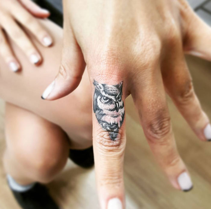 Close-up of an owl finger tattoo on a person's hand, showcasing a trendy tattoo idea.