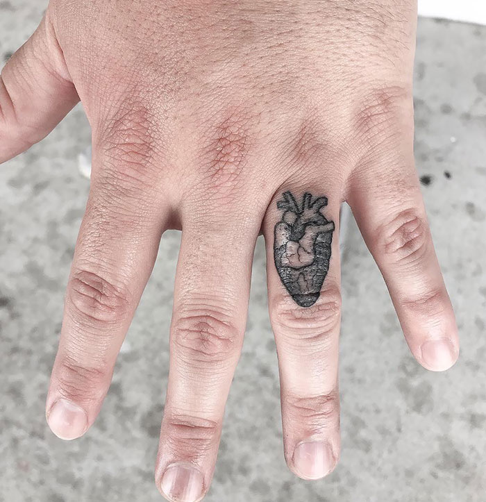 Close-up of a hand with an anatomical heart finger tattoo, showcasing the newest trend in body art.