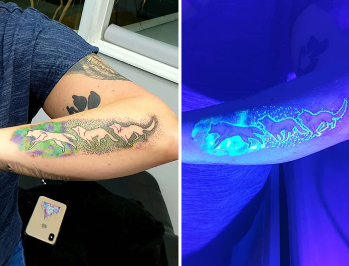 UV tattoo designs featuring glowing wolves in light and under blacklight on a person's forearm.