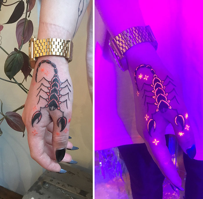 Hand with UV tattoo of a scorpion, glowing under black light, with a gold watch visible on the wrist.