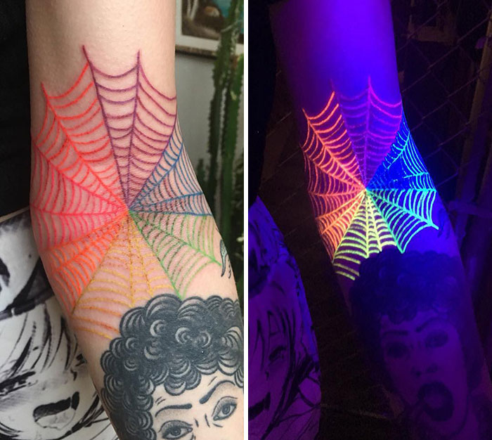 Colorful UV spiderweb tattoo glowing under blacklight.