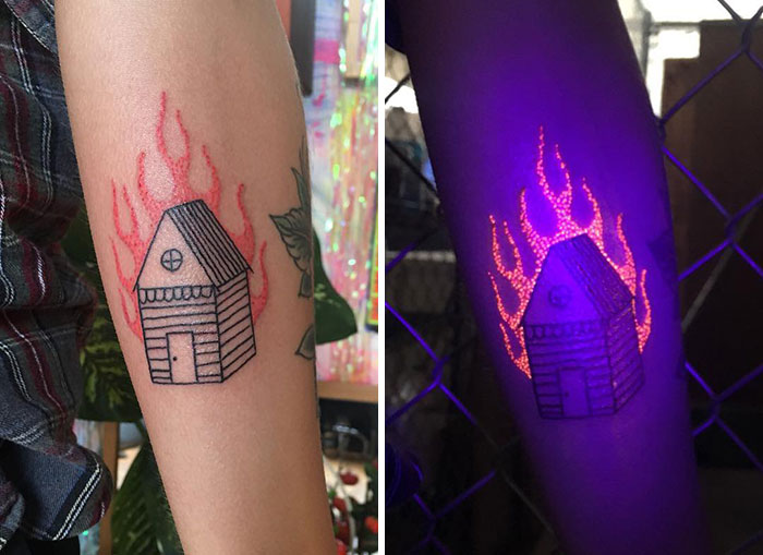 UV tattoo design of a house with flames on an arm, glowing under black light.