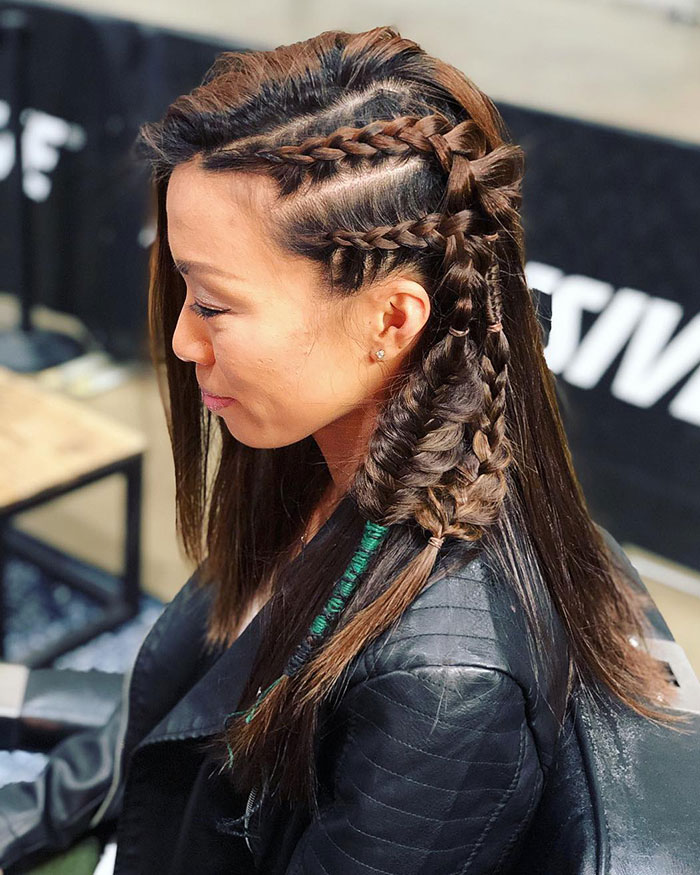 Woman with intricate Viking braid hairstyle and leather jacket, showcasing fierce modern look.