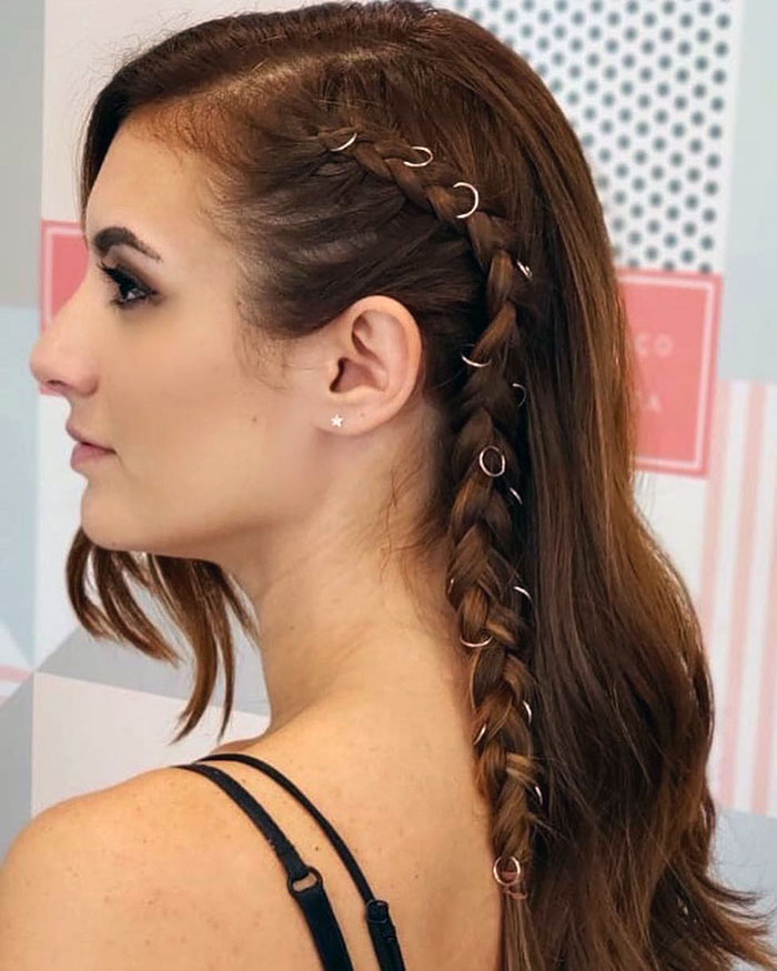Woman with a braided Viking hairstyle adorned with rings, showcasing modern Valkyrie style.
