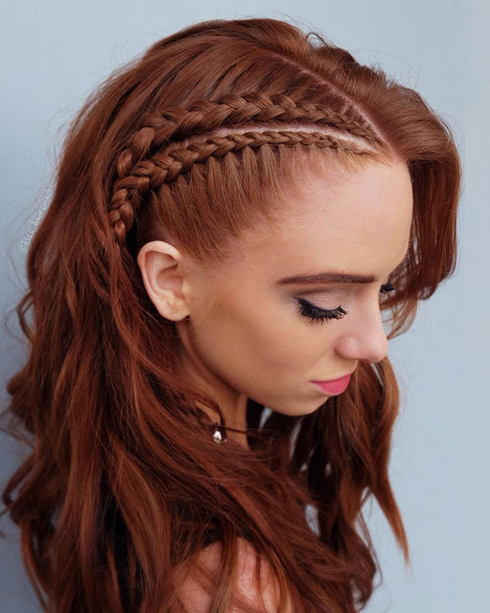 Woman with fierce Viking hairstyle featuring side braids and flowing red hair.