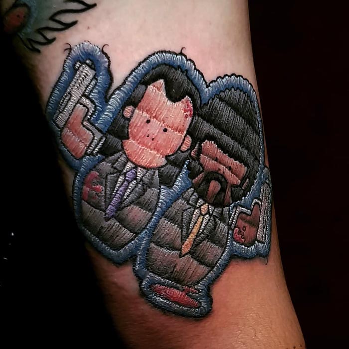 Embroidery tattoo of two cartoon characters on arm, showcasing the Brazilian tattoo artist's unique style.