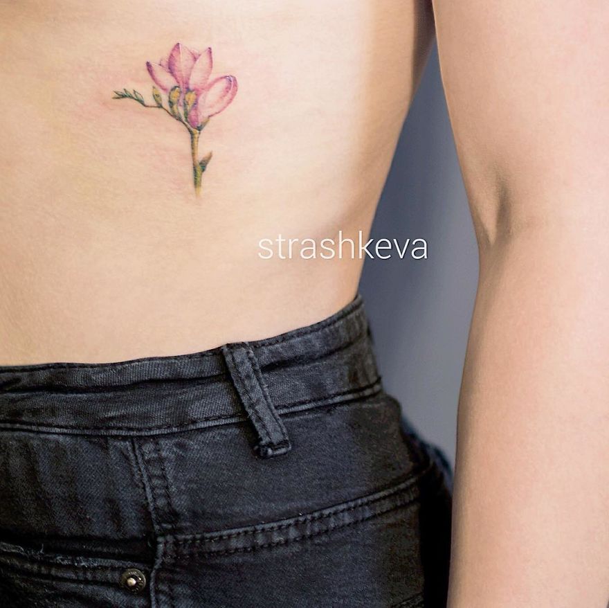 Floral tattoo by Lublin artist, showcasing delicate pink petals on the side of the torso.