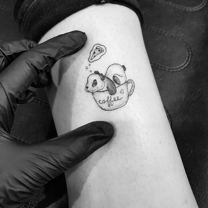 Tattoo artist from Lublin, Poland, creates a panda in a coffee cup design on a client's arm.