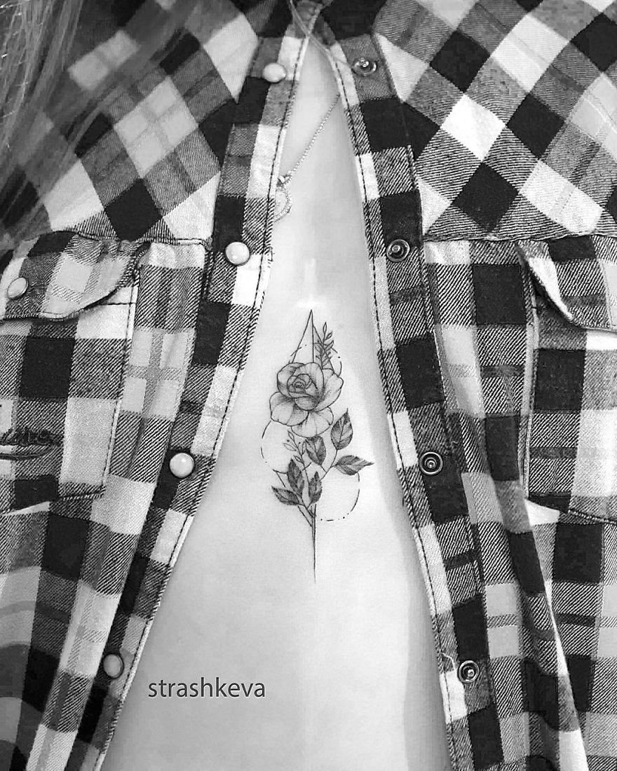 Tattoo artist from Lublin designs a floral chest tattoo, visible beneath an open plaid shirt.
