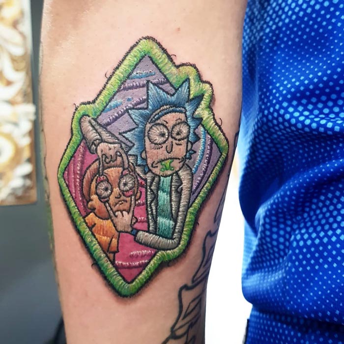 Embroidery tattoo of animated characters Rick and Morty on an arm, showcasing Brazilian tattoo artist's unique style.