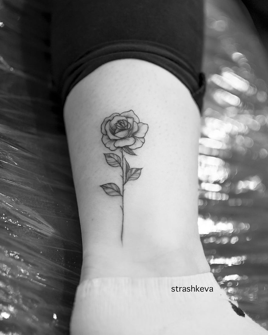 Black rose tattoo by Lublin tattoo artist on person's ankle against a reflective background.