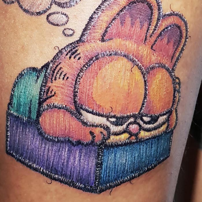 Embroidery tattoo of a cartoon cat on skin, showcasing Brazilian tattoo artistry.