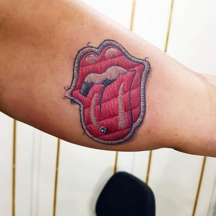 Embroidery tattoo of a tongue and lips on a forearm by Brazilian artist.