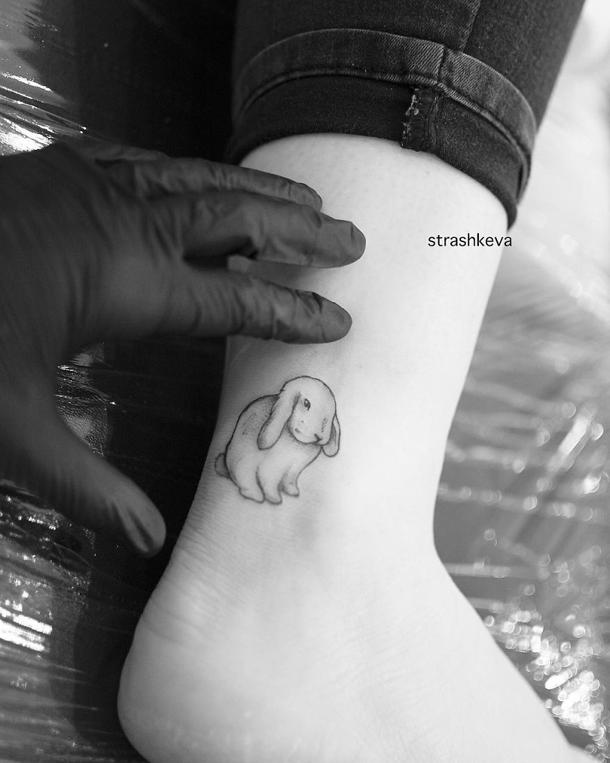 Tattoo artist from Lublin creates a rabbit tattoo on a person's ankle, with gloved hand gently touching the design.