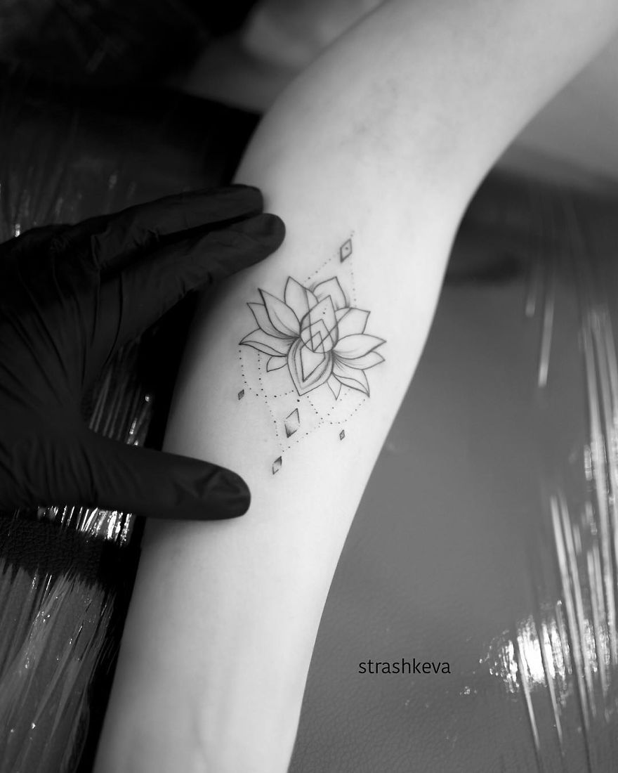 Tattoo artist from Lublin creating a geometric lotus design on an arm.