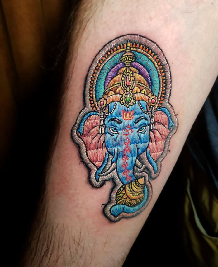 Embroidery tattoo of Ganesha on the arm, showcasing intricate design by a Brazilian tattoo artist.