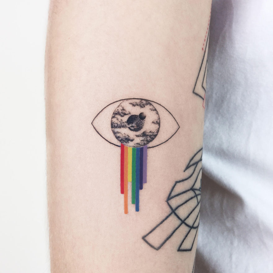 Geometric tattoo of an eye with rainbow colors and a moon design on the arm.