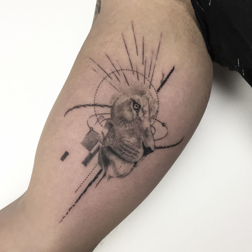 Geometric tattoo design featuring a lion head with abstract lines and shapes on a person's arm.