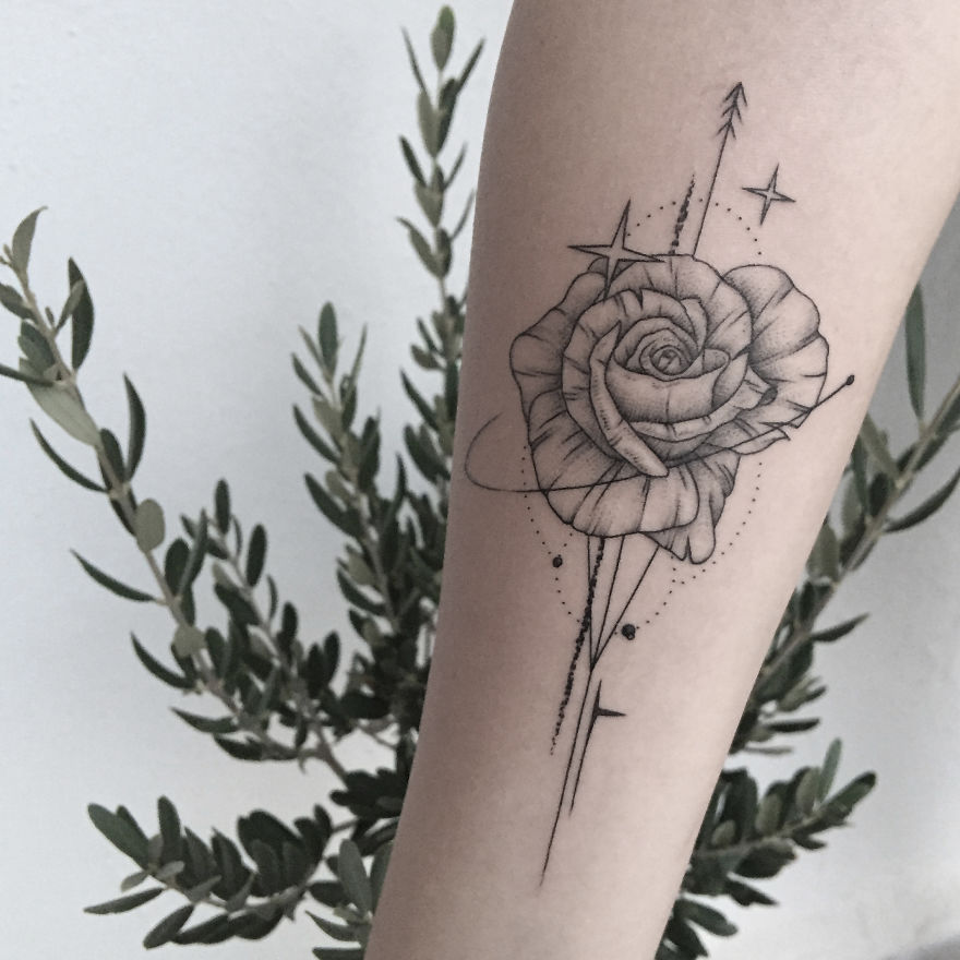 Geometric tattoo design of a rose with dotted patterns and arrows on a person's arm.