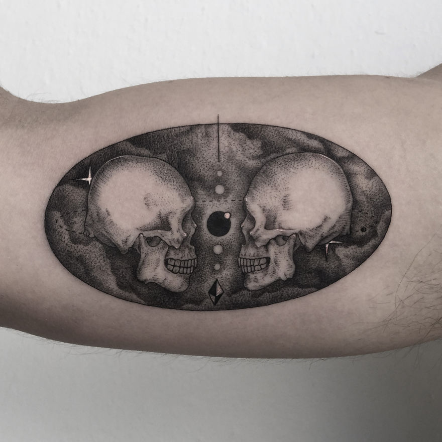 Geometric tattoo design featuring two skulls and abstract elements on inner arm.