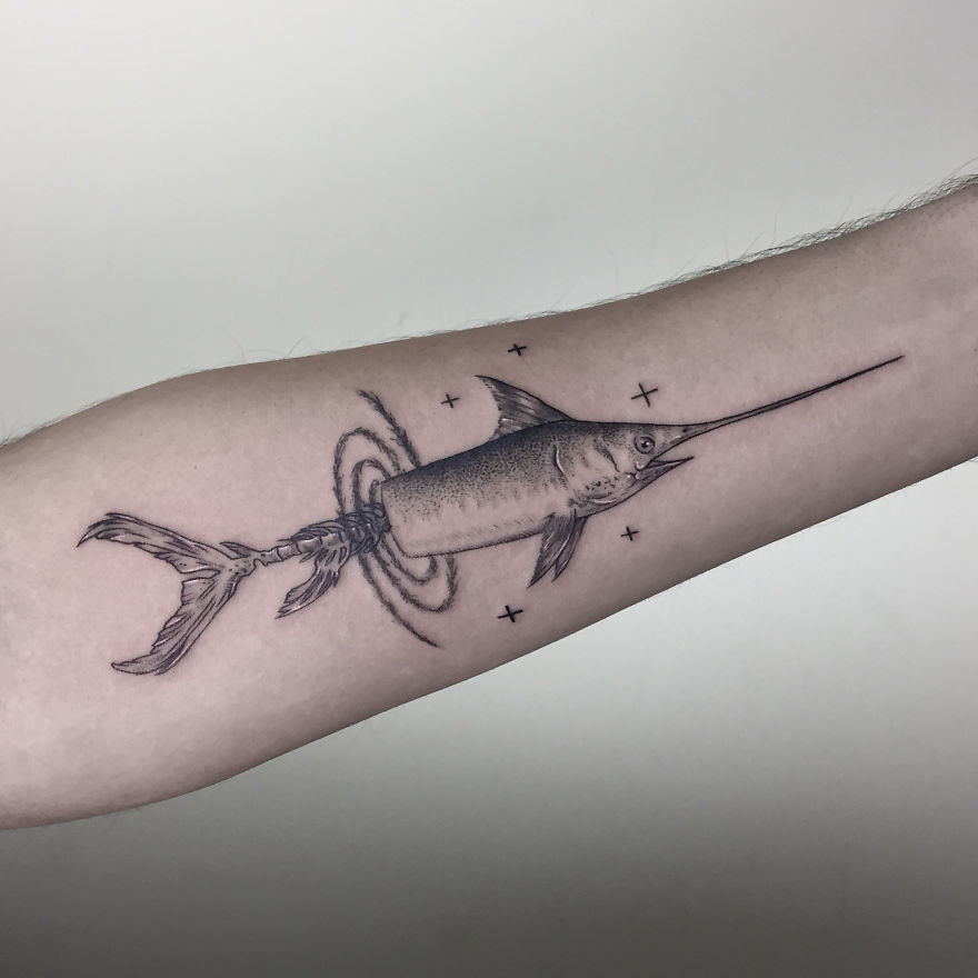 Geometric tattoo design of a swordfish on a forearm, featuring circles and stars.